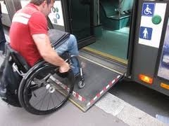 man in a wheelchair getting onto a bus with a ramp fitted to the door